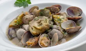 Delicioso plato de alcachofas con almejas, un manjar marino y vegetal en una salsa suave.