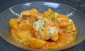 Rape en salsa marinera con patatas, adornado con perejil picado.