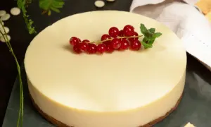Deliciosa tarta de chocolate blanco, coronada con grosellas rojas y menta fresca. Un postre elegante y cremoso.