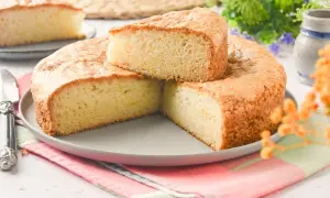 Bizcocho sin huevo esponjoso y dorado, cortado en porciones sobre un plato gris. Ideal para desayunos o meriendas.