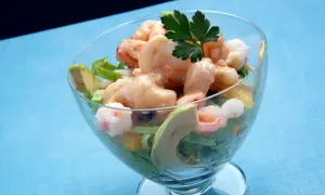 Delicioso coctel de marisco con gambas, aguacate y una cremosa salsa rosa, servido en copa.