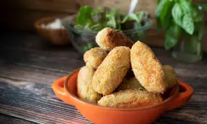 Croquetas de jamón doradas y crujientes en un cuenco naranja, listas para disfrutar.