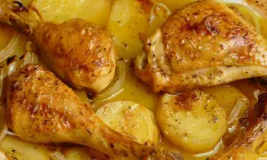 Pollo al horno con patatas y cebolla, dorado y jugoso, con hierbas aromáticas. Un plato casero irresistible.