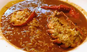 Delicioso arroz caldoso de marisco con trozos de langosta en un plato blanco.