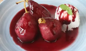 Peras al vino, tiernas y brillantes, bañadas en su jugo rojo, acompañadas de helado y menta.