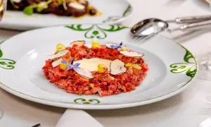 Delicioso tartar de atún fresco, adornado con láminas de trufa negra, flores comestibles y un toque de limón.