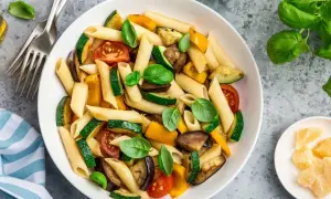 Macarrones con verduras asadas: calabacín, berenjena, pimientos y tomates, decorados con albahaca fresca. ¡Una forma deliciosa de aprender como hacer macarrones!
