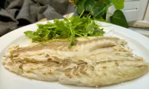 Lubina a la sal jugosa y tierna, servida con una fresca ensalada de rúcula.