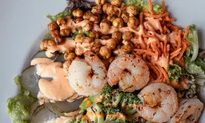 Ensalada fresca con garbanzos crujientes, langostinos jugosos, brócoli, zanahoria rallada y pepinillos encurtidos, todo bañado en una cremosa salsa rosada.
