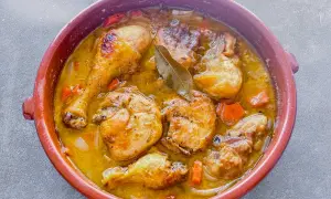 Muslos de pollo en salsa, un plato casero que evoca la receta de la abuela, con trozos de zanahoria y laurel.