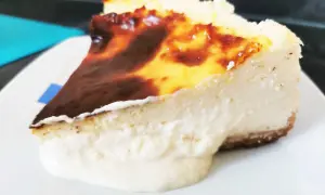 Porción cremosa de tarta de queso con la parte superior dorada y caramelizada, lista para ser disfrutada.