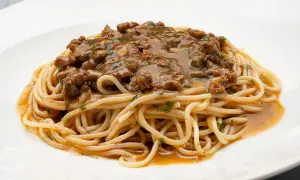 Un plato de espaguetis con una generosa porción de macarrones con carne picada, cubiertos con una sabrosa salsa.
