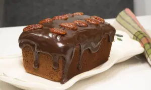 Bizcocho de plátano y chocolate cubierto de glaseado y nueces pecanas, listo para disfrutar.