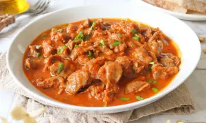Mollejas de pollo en salsa roja, un plato casero y reconfortante, servido en un cuenco blanco con perejil picado.