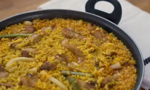Paella recién hecha, un plato perfecto para tus recetas de arroz. Con trozos de carne, judías verdes y un arroz amarillo vibrante.