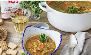Un delicioso arroz con bogavante, servido en un cuenco con perejil fresco. A su lado, galletas saladas y una copa de vino blanco.