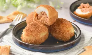 Deliciosos huevos rellenos rebozados, crujientes por fuera y jugosos por dentro, servidos en un plato con galletas saladas.