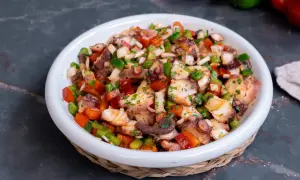 Un refrescante salpicón de pulpo con pimientos, cebolla y perejil, listo para disfrutar.