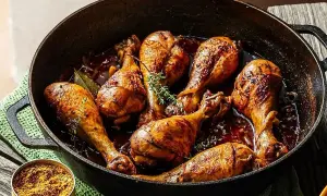 Muslos de pollo a la cerveza dorados y jugosos en una sartén de hierro fundido, con hierbas frescas y un toque de especias.