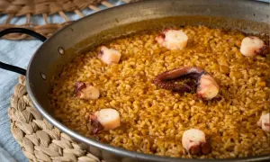 Arroz con pulpo en paellera, con trozos de pulpo bien visibles entre el arroz dorado.