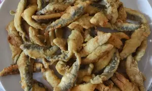 Un plato lleno de boquerones a la andaluza, crujientes y dorados, listos para disfrutar.