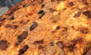 Arroz con costra dorado y crujiente, con trozos de carne y aceitunas negras incrustados.