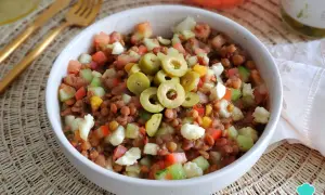 Ensalada de lentejas de bote con tomate, pepino, pimiento y queso fresco, coronada con aceitunas verdes. ¡Un plato fresco y nutritivo!