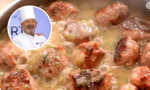Chef sonriente presenta un plato de albóndigas con patatas en salsa cremosa, decorado con perejil picado.