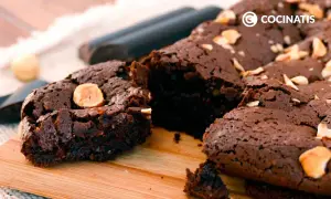 Delicioso brownie sin gluten, con trozos de avellana, sobre una tabla de madera.