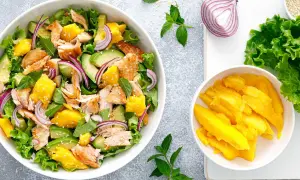 Ensalada de mango con salmón desmenuzado, aguacate, cebolla morada y hojas verdes. ¡Una explosión de sabor!