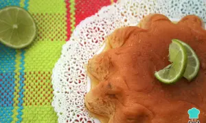 Delicioso flan de limón con rodajas de lima, servido sobre un mantel colorido y un encaje blanco.