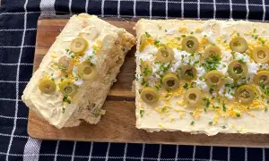 Un delicioso pastel de atún, decorado con aceitunas, huevo rallado y cebollino.