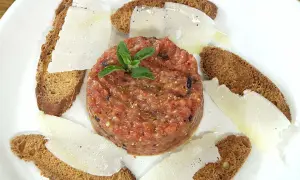 Tartar de tomate fresco, servido con finas láminas de queso y tostadas crujientes. Un bocado ligero y lleno de sabor.