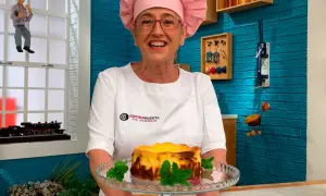 Chef sonriente presenta una deliciosa tarta de queso La Viña, decorada con menta fresca.