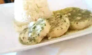 Merluza en salsa verde, un plato delicioso con pescado blanco bañado en una sabrosa salsa de perejil y ajo, acompañado de arroz blanco.