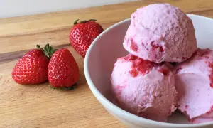 Bol con helado de fresa cremoso y trozos de fruta fresca.