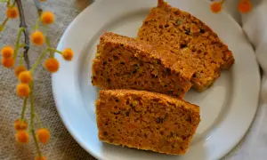 Rebanadas de tarta de zanahoria casera, esponjosas y con trocitos de zanahoria, servidas en un plato blanco.
