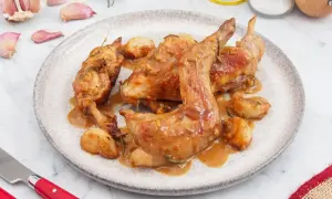 Delicioso conejo al ajillo servido en un plato, con trozos de ajo asado y romero.