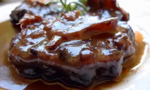 Rabo de ternera estofado, jugoso y tierno, bañado en su propia salsa oscura y aromática, con un toque de romero fresco.