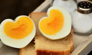 Dos mitades de huevo cocido, con forma de corazón, sobre tostadas. Ideal para saber cuanto tarda en cocer un huevo y disfrutar de un desayuno.