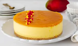 Deliciosa tarta de mango con una capa superior de gelatina brillante y decorada con granos rojos y amarillos.