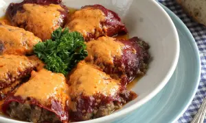 Pimientos rellenos de carne cubiertos con una cremosa salsa, decorados con perejil fresco.