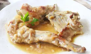 Sabroso conejo en salsa, servido en un plato blanco con una ramita de perejil.