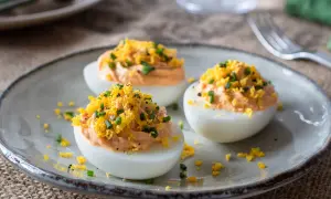 Huevos rellenos de atún, decorados con ralladura de huevo y cebollino. Un aperitivo delicioso y fácil de preparar.