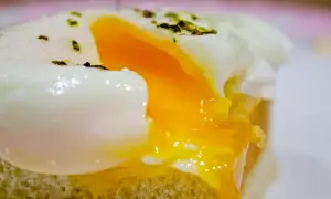 Un huevo poche microondas perfecto, con la clara cuajada y la yema líquida, servido sobre una tostada.