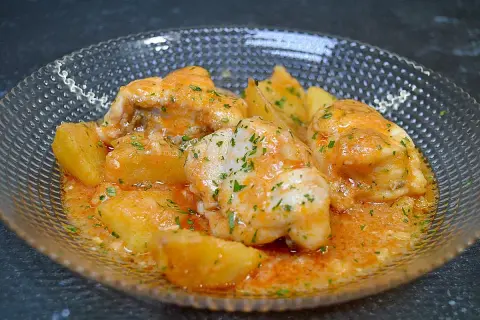 Rape en salsa marinera con patatas, adornado con perejil picado.