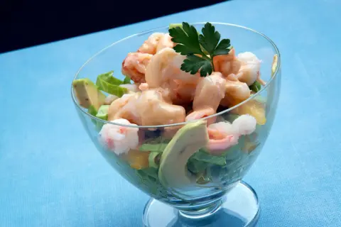 Delicioso coctel de marisco con gambas, aguacate y una cremosa salsa rosa, servido en copa.