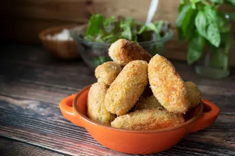 Croquetas de jamón doradas y crujientes en un cuenco naranja, listas para disfrutar.