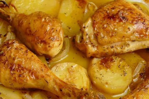 Pollo al horno con patatas y cebolla, dorado y jugoso, con hierbas aromáticas. Un plato casero irresistible.