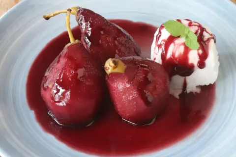 Peras al vino, tiernas y brillantes, bañadas en su jugo rojo, acompañadas de helado y menta.